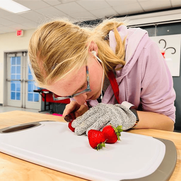 A student cuts a strawberry.