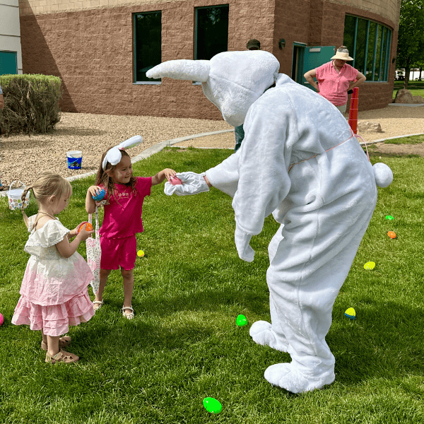 Two young girls are hunting for eggs with the help of the Spring Bunny.