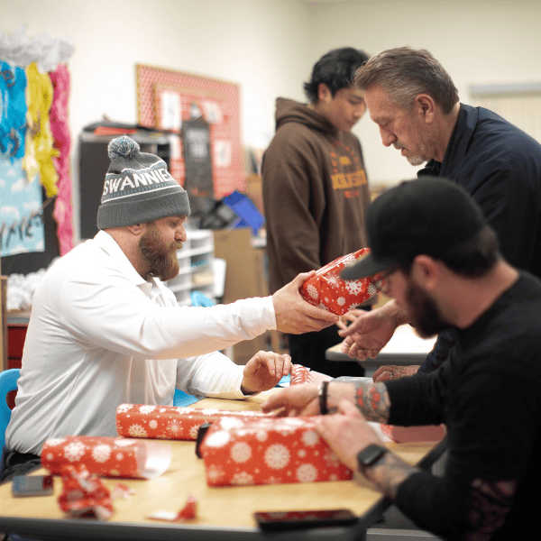 Volunteers wrap gifts at a holiday party.